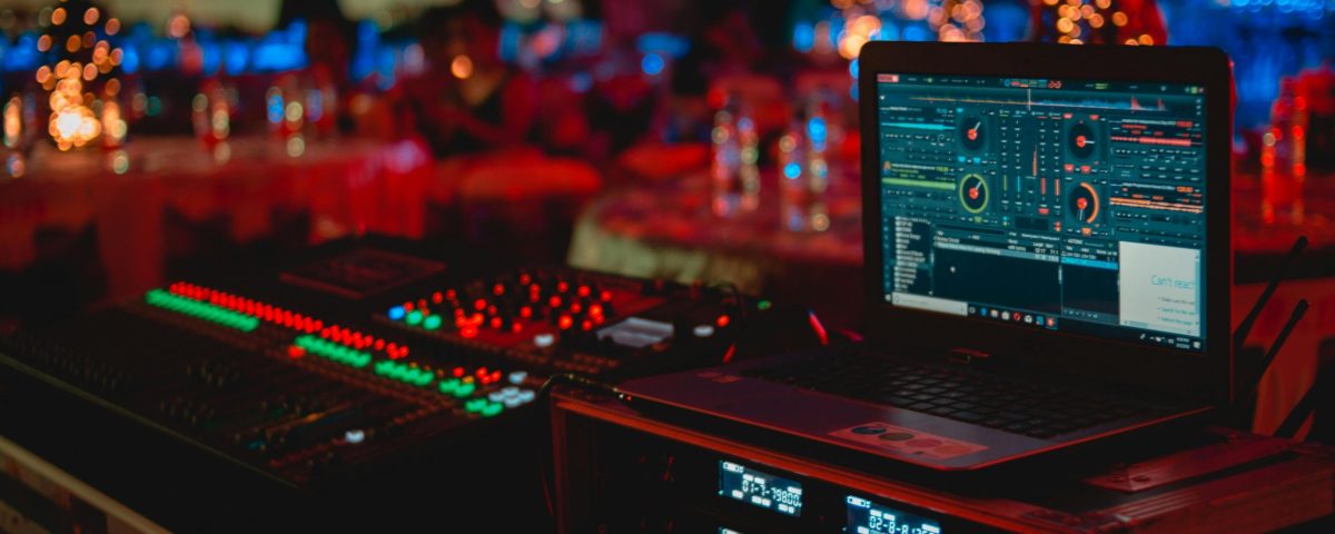 Vivid DJ setup with laptop and sound mixer at a lively indoor event.
